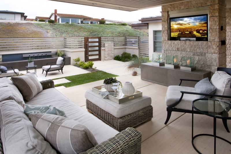 What used to be an understated, grassy front yard now is a modern and sophisticated outdoor beach retreat. Simple lines and light colors serve as a backdrop for the space that features all the modern amenities often reserved for the backyard: built-in flat screen TV with retractable cover, fire feature, water element, multiple seating areas, even heat. A sleek fence and stylish door provide enough coverage to make the street-facing yard private for the entire family to enjoy.
