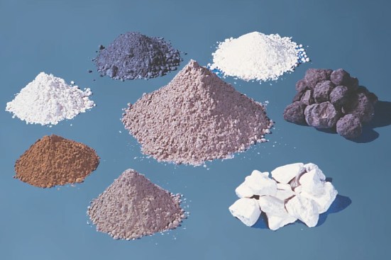 A blended cement (could be a pozzolan, slag, or limestone blend) is seen in the center, with the dark gray nodules called clinker to the right. Clockwise from the clinker are gypsum, portland cement, fly ash, slag, silica fume, and calcined clay.