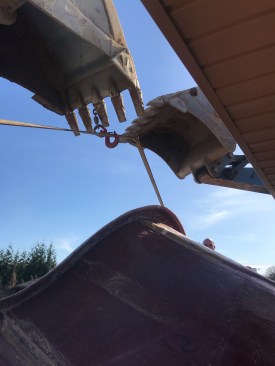 Installers transfer the pool from one excavator to the other, affixing it onto the smaller machine.