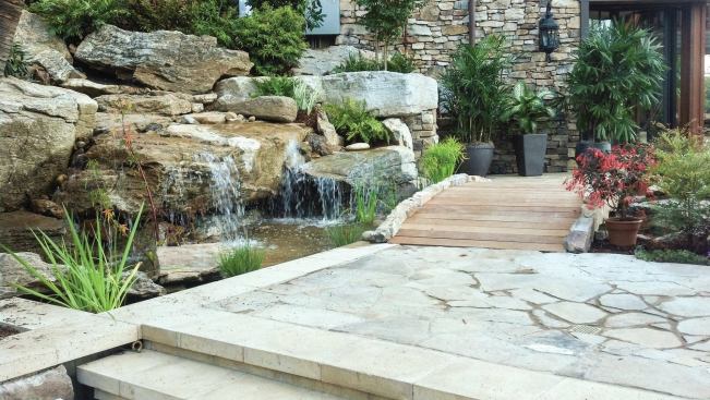 Piecing a natural puzzle: The homeowners asked for a stream and rock waterfeature with a wide fall. A 300-foot stream comes from the upper property down near the pool before spilling over into the final basin. The bottom fall required the right kind of stone. “To make this wide waterfall appear natural, that rock had to look like it had always been there,” Dorsey says. “It had to look like bedrock — a large rock with horizontal grain. “If the grain of a rock in nature is tilted up, you won’t have a wide waterfall. It’ll be coming off the side, in a narrow little gush of water.” There are two kinds of waterfalls in nature, he explains — the type involving large stones like his customer wanted, and others with smaller colluvial rocks that are more jumbled, less structured. “Colluvial waterfalls are generally not very high, and they exhibit concentrated flows,” he says. “Bedrock situations are the only time you get the Niagara Falls look, the Yosemite Falls.”