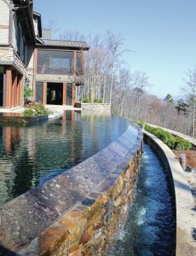 Sweeping View: The 77-foot-long vanishing-edge pool forms a sweeping arc connecting the main house with the guest house, seen in the top image. A black pebble finish adds to the reflective quality and adds a modern touch, while the Tennessee fieldstone deck ties with the home’s rustic materials.