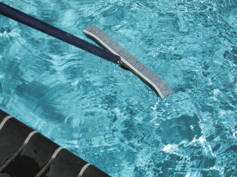 3a. If the tear is reachable from the deck, you can place the patch over the damaged area by hand. Do it quickly because the glue doesn’t take long to dry — even under water. Note: Smooth over the edges around the tear with fine sandpaper. 3b. If the rip is in the deep end and you can’t get into the water, you can try a clever method to finish the job. After gluing the patch, drop it into the water and let it settle by the tear, guiding it with a pool brush. 